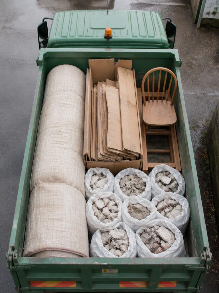 Green tipper truck neatly loaded with sorted household waste ready for licensed disposal